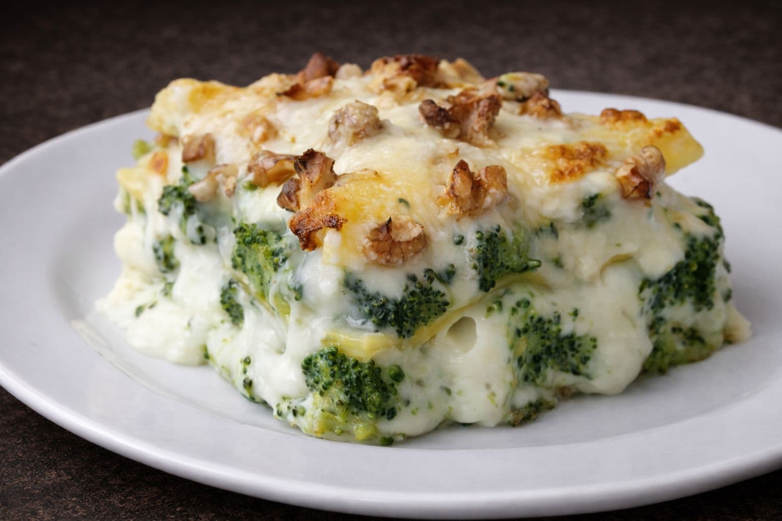 Lasanha de brócolis com bacon gratinada, servida em refratário.