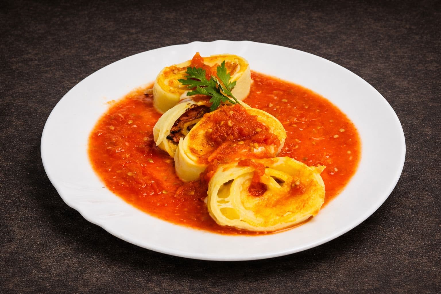 Rondelli de presunto e queijo servido em travessa com molho sugo.